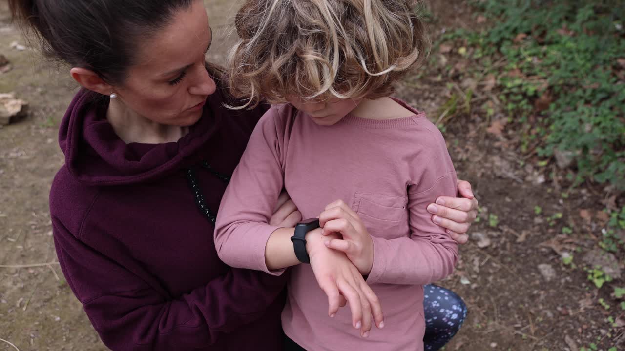 mamá explicando a su hijo cómo usar un reloj de pulsera al aire libre