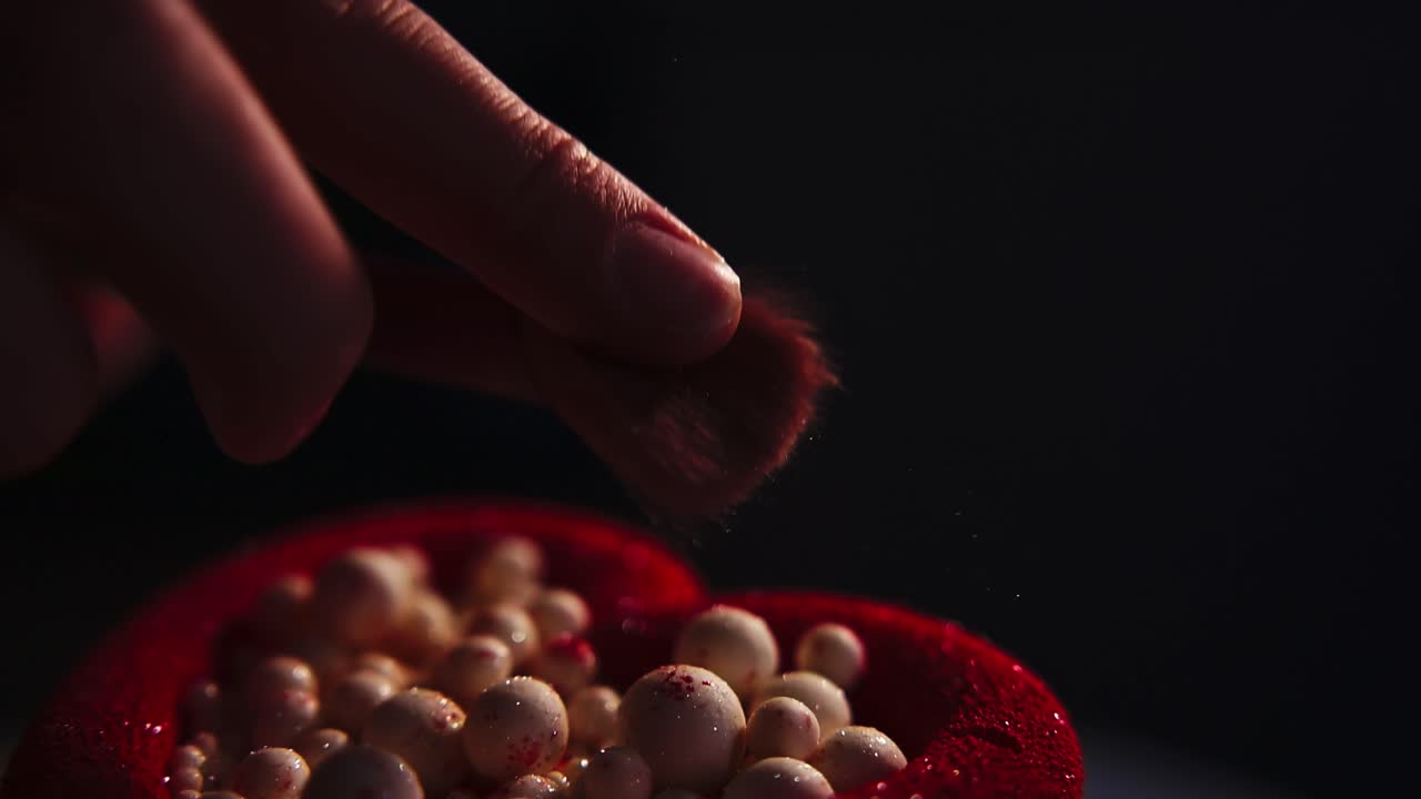 Primo piano di pennello da trucco che picchietta la cipria su perle cosmetiche