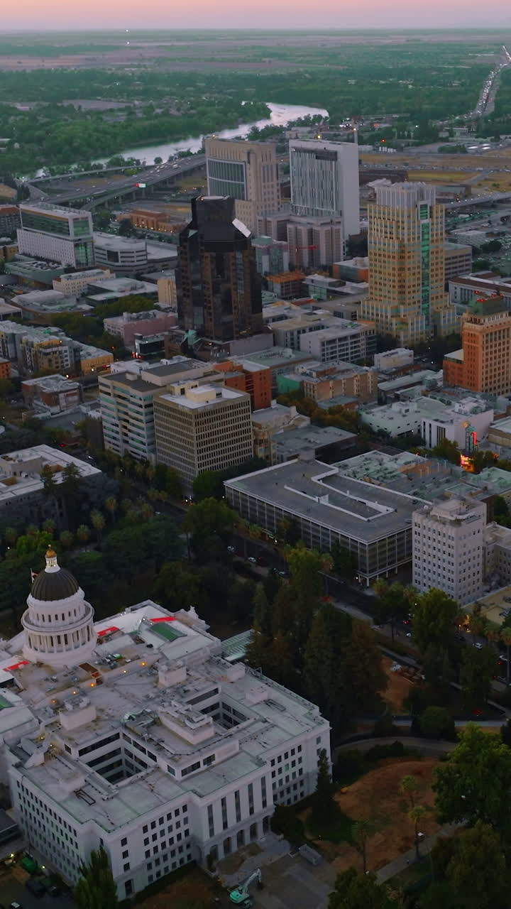 Modern architecture of Sacramento downtown in the evening. River and green landscape at backdrop. Top view. Vertical video