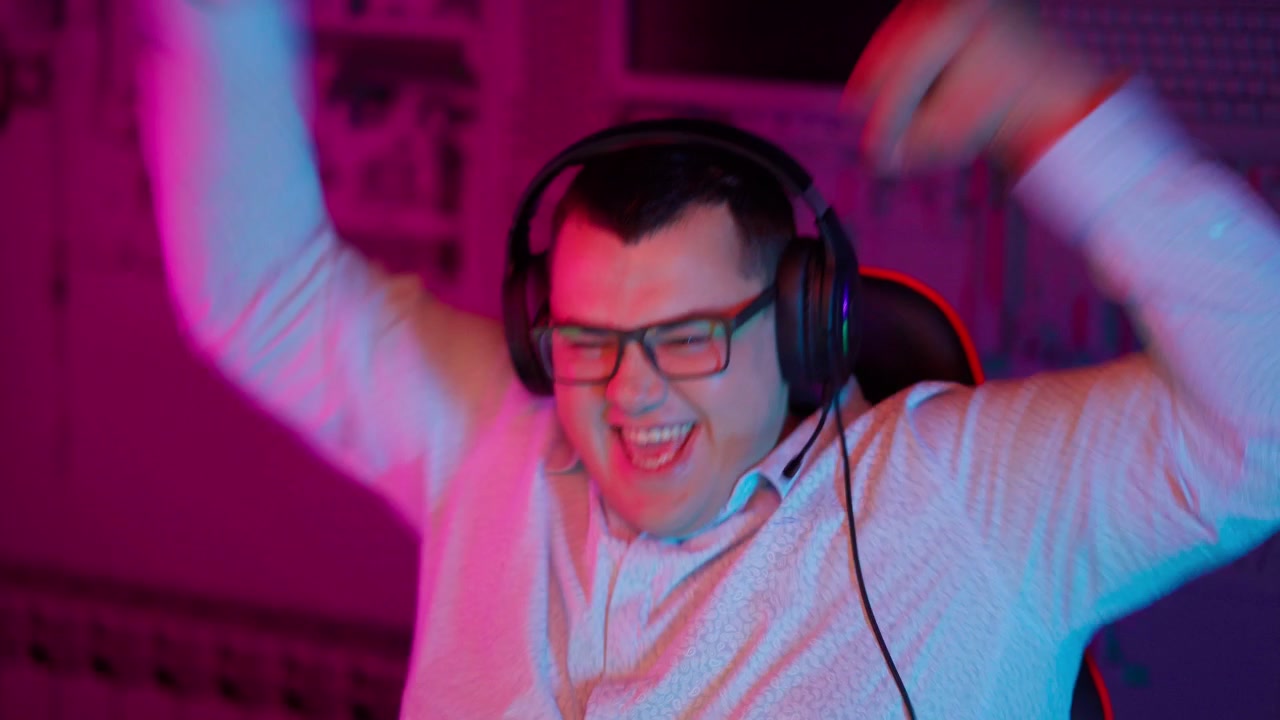Giovane uomo entusiasta con cuffie che celebra una vittoria nel gaming.