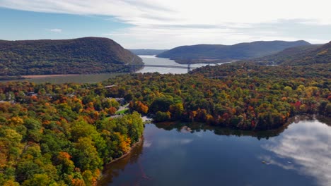 an aerial view over a reflective lake with colorful trees during the fall foliage in upstate ny