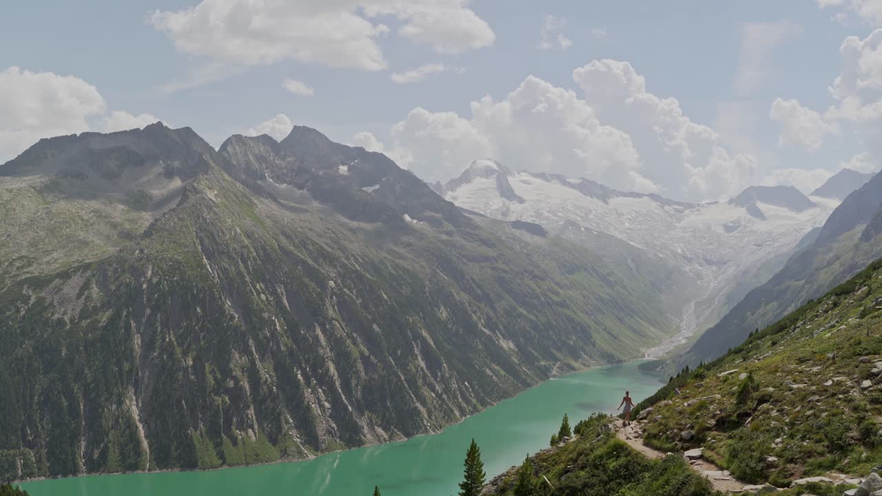 하얀 드레스를 입은 백인 소녀가 노출된 산길을 걷고 있다