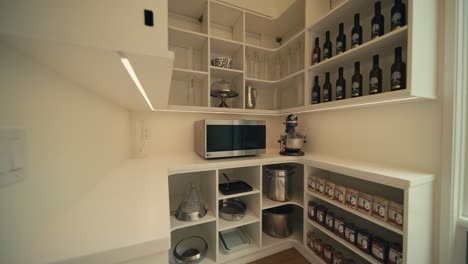 a neatly decorated pantry in a luxury home with oils, cooking, ingredients, and a microwave