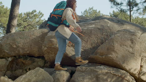 red haired woman backpacker climbing mountain hill while hiking on a sunny autumn day in the forest 1