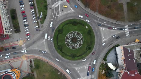 vista aérea de 4k de la carretera de rotonda con coches circulares en una pequeña ciudad europea en un día nublado de otoño