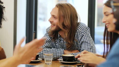 close-up view of multiethnic group of friends talking and laughing sitting at a table in a cafe