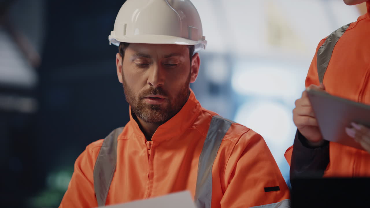 dos técnicos discutiendo la documentación técnica trabajando en la fábrica de cerca.