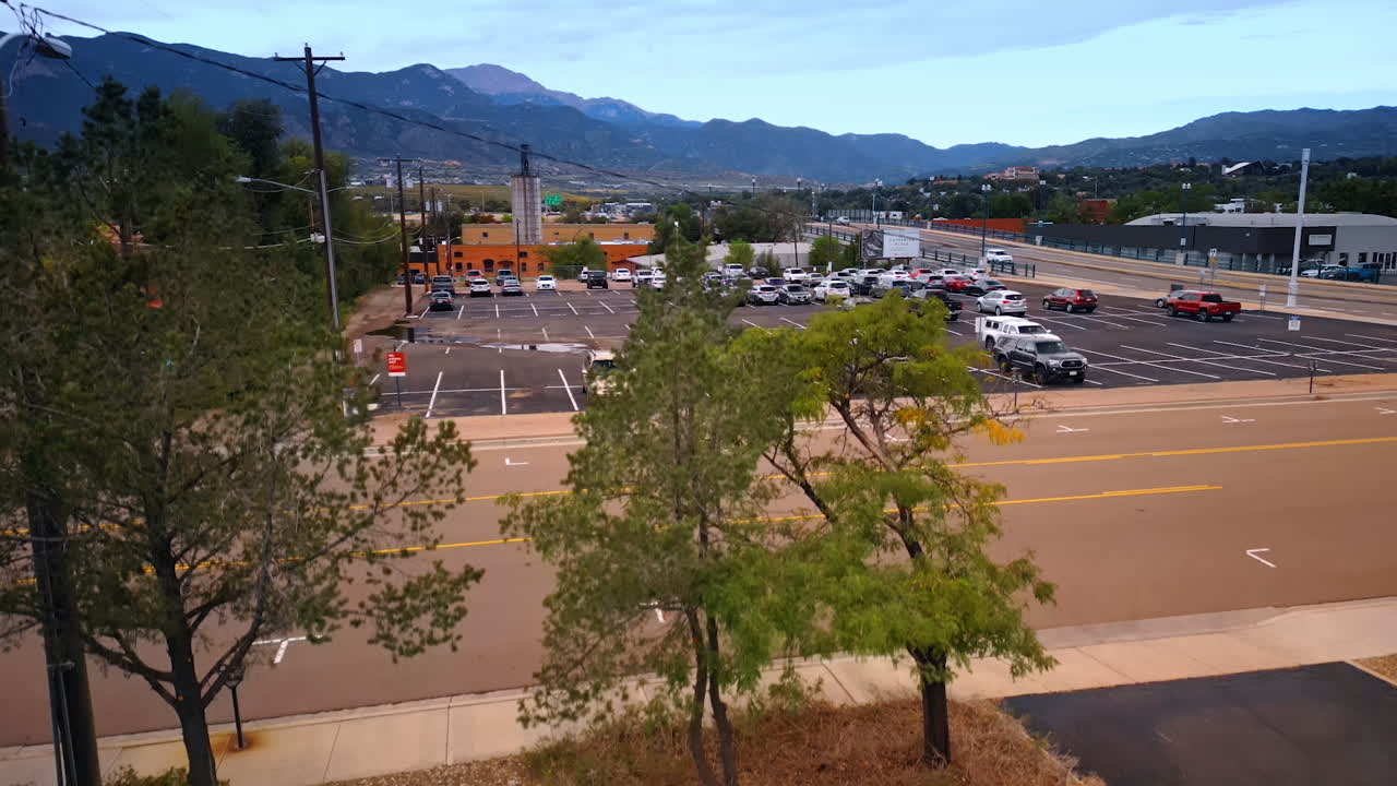 Colorado Springs, USA, 22 July 2025: Big parking lot half-busy with cars. Scenery of Colorado Springs, Colorado, USA. Mountains at backdrop