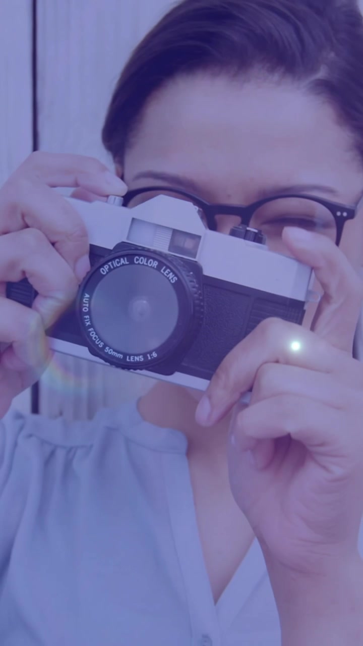 Punto luce su una fotografa afroamericana che scatta foto con una fotocamera digitale