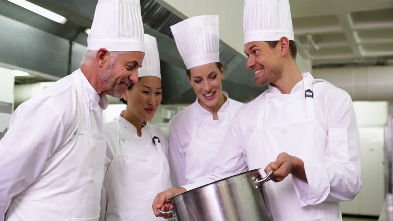 chef mostrando a sus colegas el contenido de una olla grande