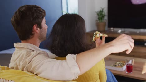 video de la vista de atrás de una feliz pareja diversa comiendo pizza y abrazándose