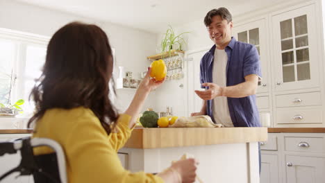 pareja asiática madura con esposa en silla de ruedas desempaquetando productos frescos en la cocina después de un viaje de compras - filmado en cámara lenta