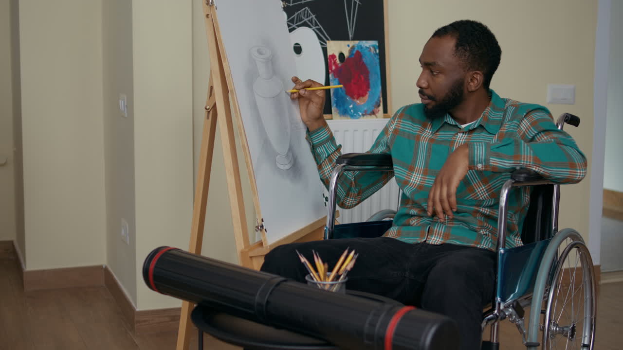 Uomo afroamericano con disabilità che usa una matita per disegnare su aree di lavoro