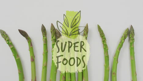 super foods text animation over fresh asparagus on white background