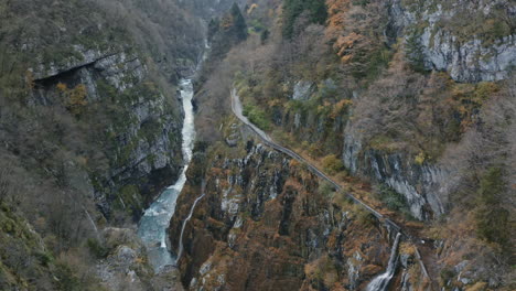 top down aerial drone view of water stream flowing along rocky ravine in mountain woods