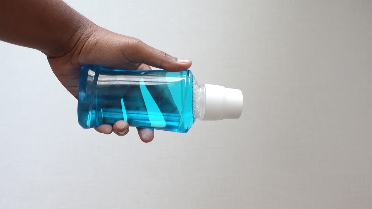 mano con una botella de enjuague bucal