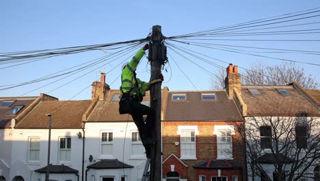 Telecommunication engineer performing maintenance on cables at the top of a telephone pole