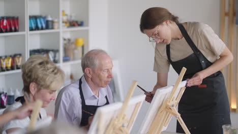 side view of a happy senior people smiling while drawing as a recreational activity or therapy in paint class together with the group of retired women and men