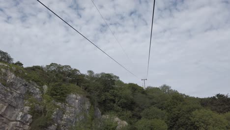 Passing-red-cable-car-sightseeing-transportation-heading-up-scenic-mountain-valley-hillside