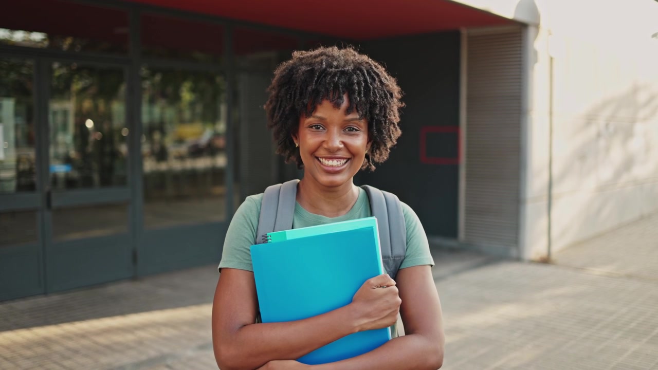 Glad afroamerikansk student smiler med bøker på campus
