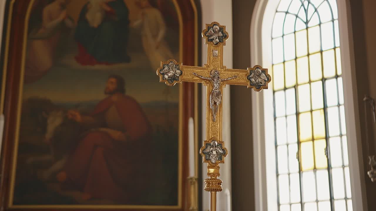Golden cross in church interior with stained glass window