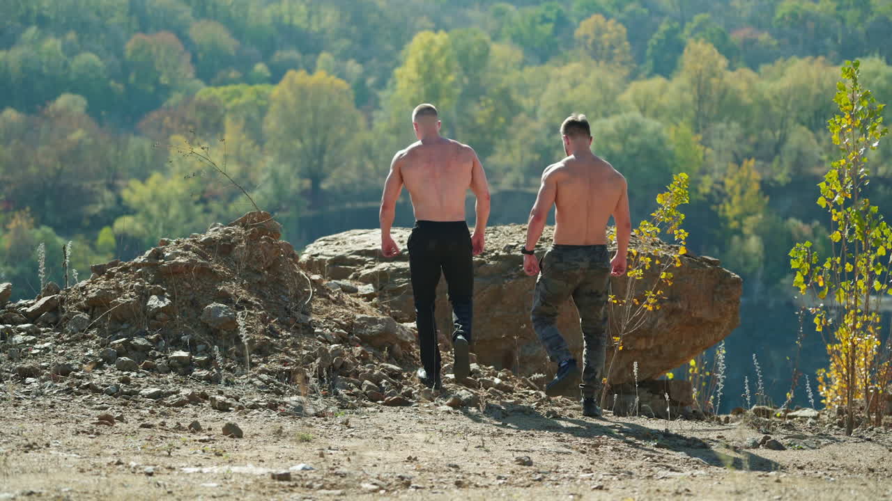 Muscular strong fit athletes. Rear view of handsome young athletes outdoors