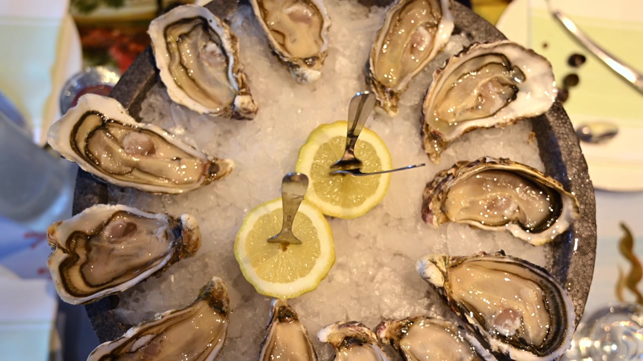Ostriche fresche esposte su ghiaccio tritato con fette di limone in un ambiente da ristorante di pesce.