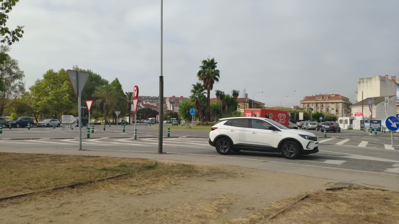 time lapse of traffic of cars and trucks flowing without incident in a roundabout with vertical signs one gray morning with clouds, blocked shot. Porto-novo, Galicia, Spain