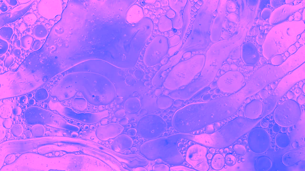 Colorful oil drops floating on water surface, top view. Fantastic abstract background. Bright bubbles moving and spreading. Close up 4k video of weird liquid structures. Scientific chemical experiment