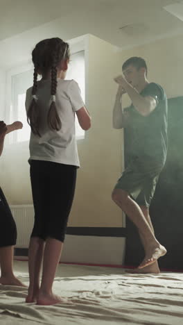 children punch air following trainer in martial arts class. junior sportsmen study attacking by hands with master in gym slow motion. healthy kids