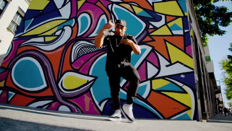 man dancing in front of colorful graffiti wall