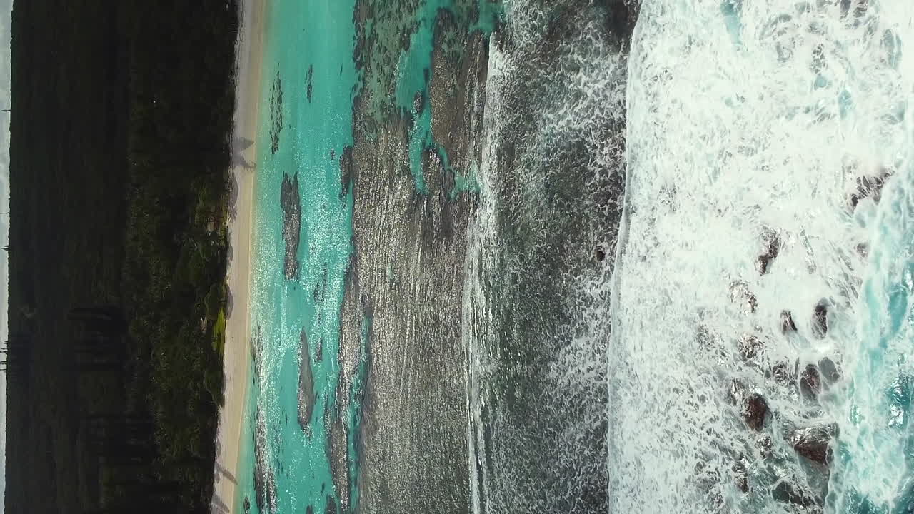 Ripresa aerea di onde che si infrangono sulla barriera corallina sulla spiaggia di Yejele, Nuova Caledonia.