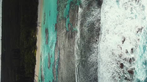 Aerial-shot-of-waves-breaking-over-reef-on-Yejele-Beach,-New-Caledonia