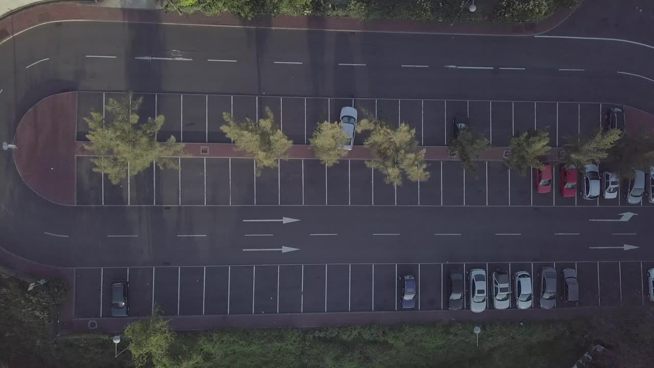 Top down view of oval parking lot with stationed cars in natural environment - Aerial
