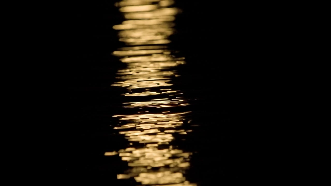 Riflesso di luce dorata scintillante sull'acqua scura di notte