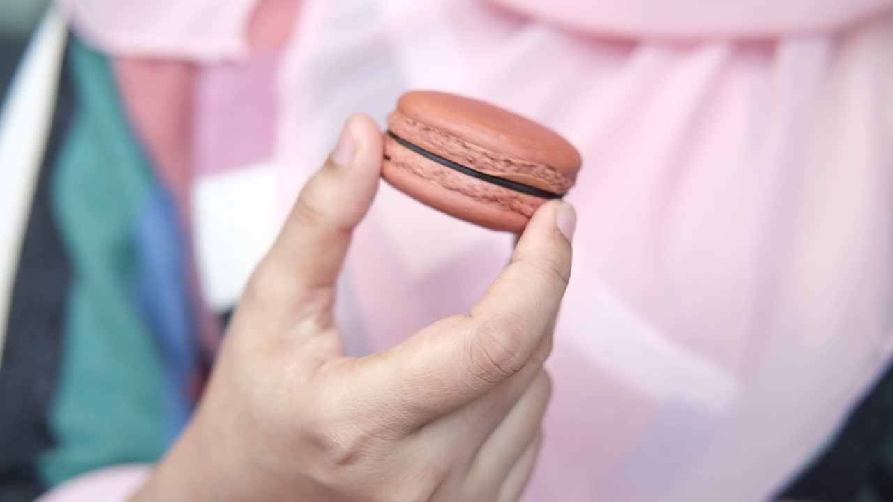 mano con un macarrón rosado