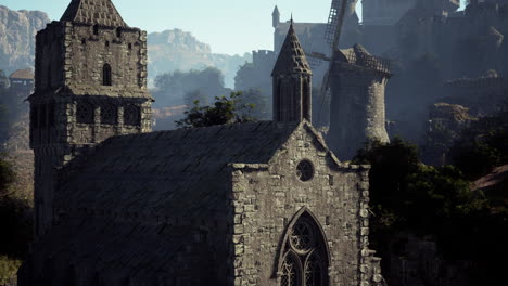 a stone church with a steeple, a windmill and a village in the background