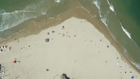 Vertikale-Luftaufnahme-Von-Oben-Nach-Unten-Von-Ruhigen-Meereswellen,-Die-Den-Strand-Treffen,-Der-Mit-Touristen-Besetzt-Ist,-Die-Das-Sonnige-Wetter-Am-Strand-Von-Tel-Aviv-Genießen