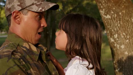 papá militar feliz sosteniendo a su pequeña hija en brazos