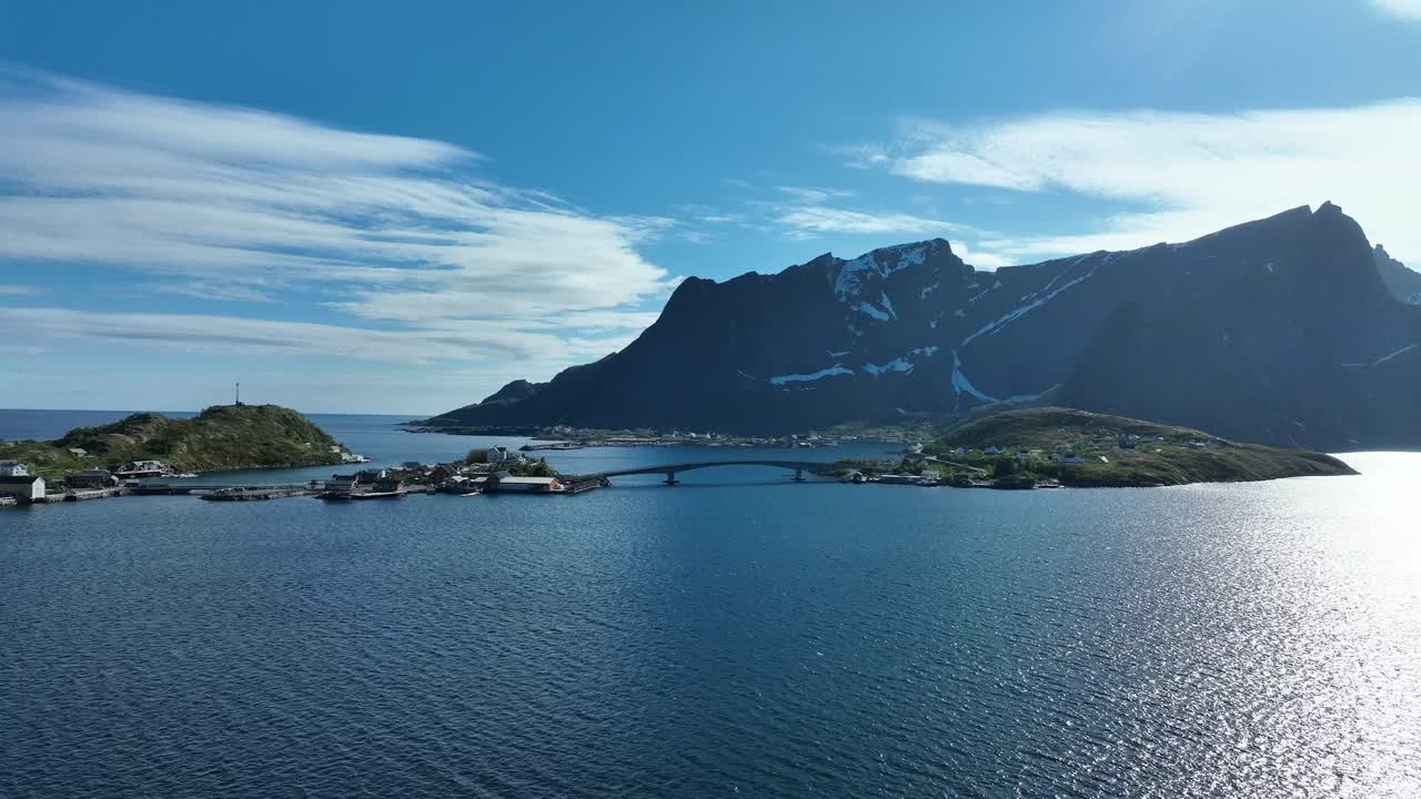 Iconic Reine bridge in Lofoten with village and Reinebringen mountain in background over calm sea