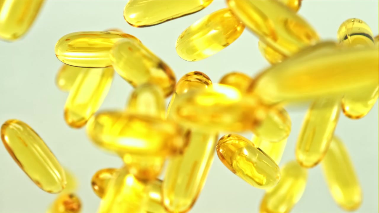 Capsule gialle di Omega 3 che cadono al rallentatore