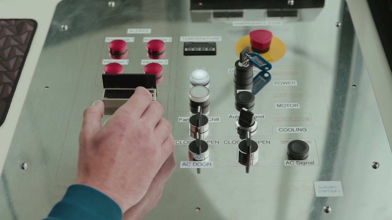 Hand pressing controls on metal panel with switches buttons and safety key