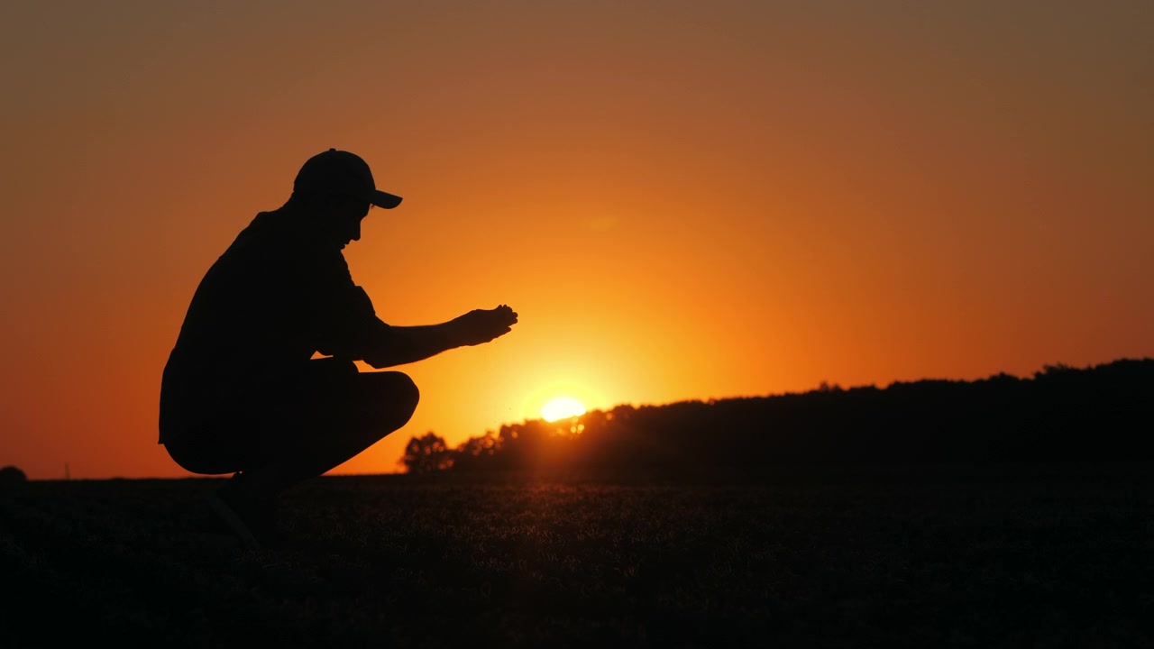Farmer Holding Soil in Silhouette at Sunset
