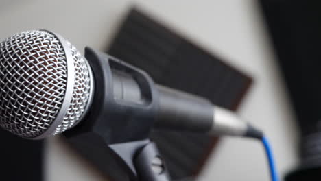 close up on a music studio vocal microphone being adjusted by the singer during a recording session with a pop filter