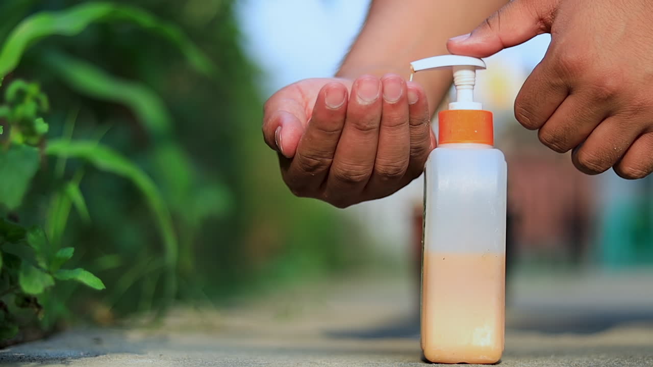 Low angle pouring liquid soap on hands outdoors to wash and protect from coronavirus