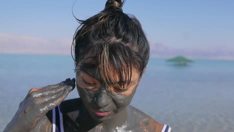 mujer asiática usando barro en el mar muerto