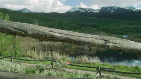 Camera-Push-through-Wood-Fence-Scenic-Landscape-with-Forest-Trees-in-Colorado-Snow-Capped-Mountains