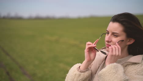 A-Young-Beautiful-Brunette-Girl-Puts-On-Sunglasses-In-A-Green-Meadow