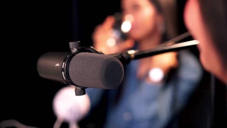 Unrecognizable-woman-being-interviewed-in-a-radio-station-studio-while-live-on-air,-selective-focus