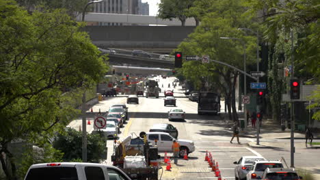 car and people hustle around a construction zone in a city